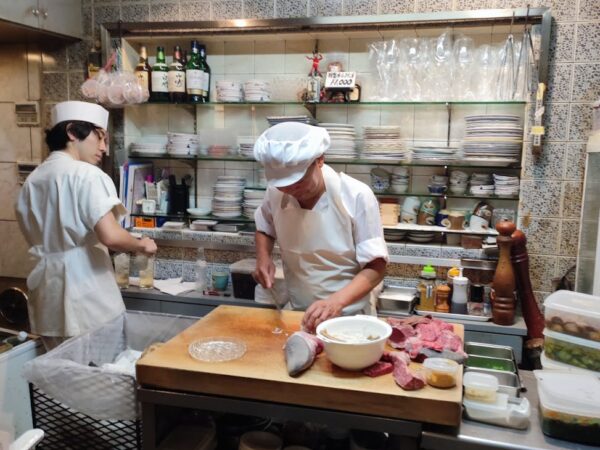 two chefs in a kitchen preparing food in a small room
