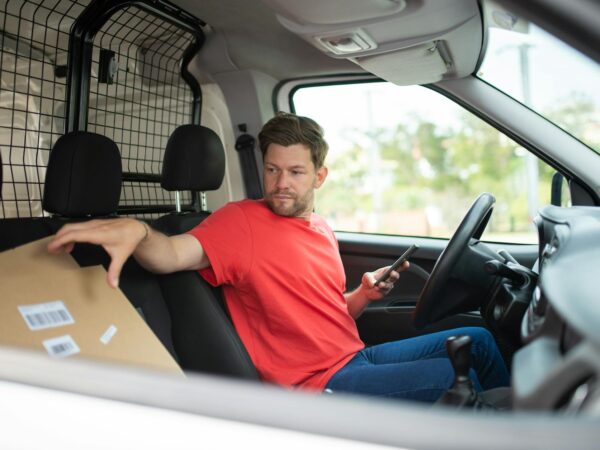 a man sitting in the driver sear of a van holding a cardboard box